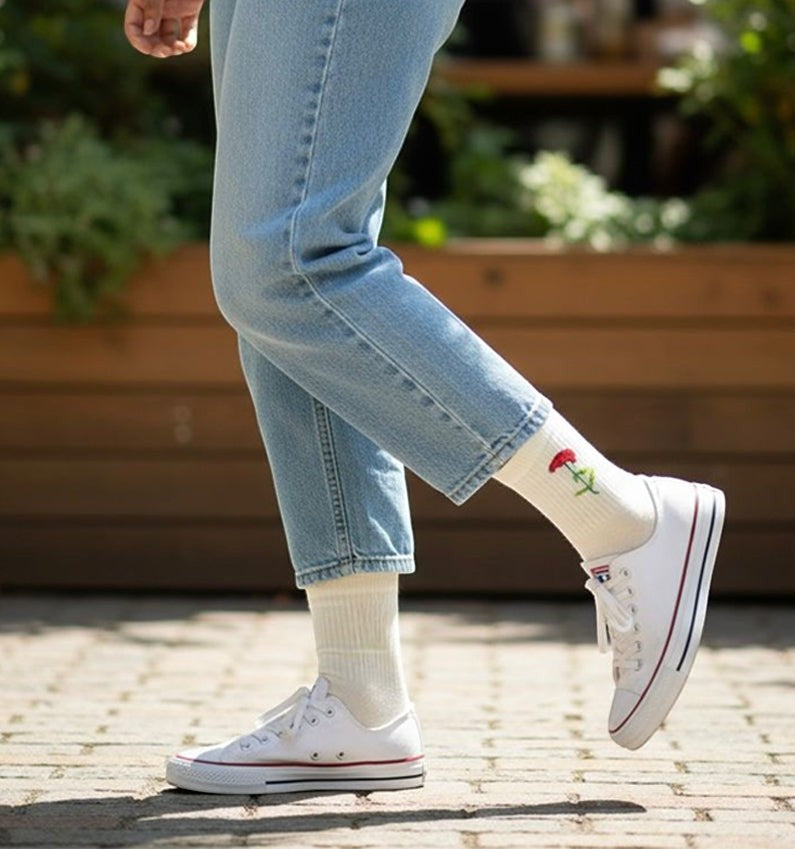 Qorapa LaraLara white crew socks with red floral embroidery worn with blue jeans and white sneakers outdoors