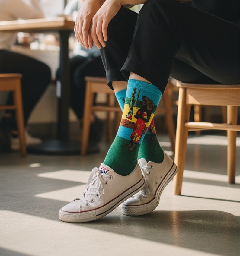 Qorapa LaraLara crew socks featuring a vibrant multi-colored graphic print worn with white sneakers and black trousers