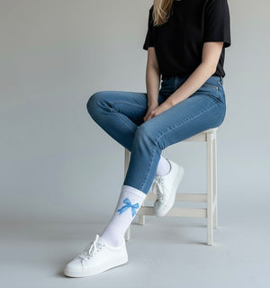 Qorapa LaraLara white crew socks with a blue bow print worn by a person in jeans and white sneakers