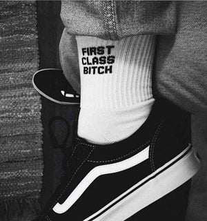 Qorapa LaraLara white crew socks with black graphic text worn with black sneakers and denim jeans