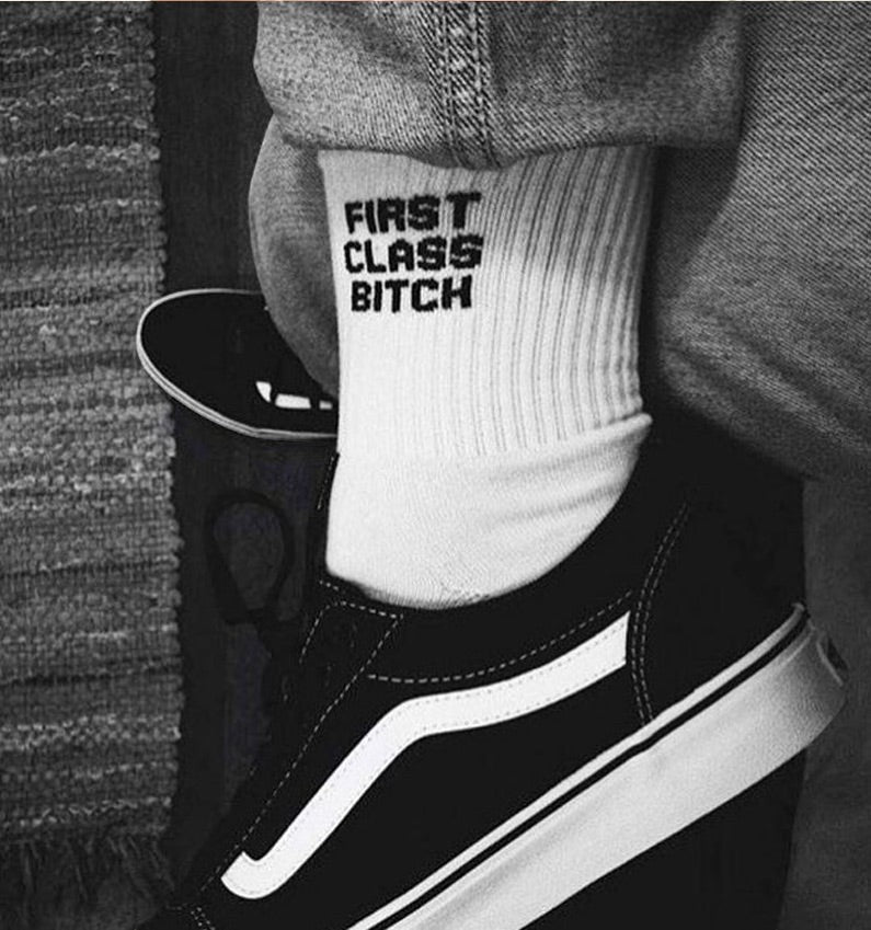 Qorapa LaraLara white crew socks with black graphic text worn with black sneakers and denim jeans