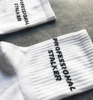 Qorapa LaraLara white cotton-blend crew socks featuring black embroidered PROFESSIONAL STALKER text on the ribbed cuff.