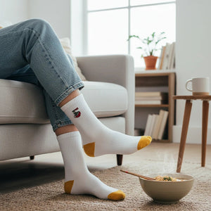 Qorapa LaraLara white crew socks with ramen bowl embroidery and mustard yellow heel and toe caps worn by a person.