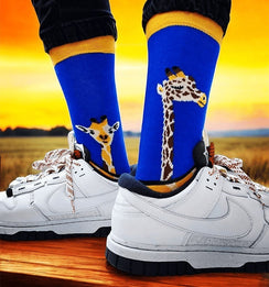 Qorapa LaraLara royal blue crew socks with giraffe pattern and yellow cuffs worn with white sneakers at sunset