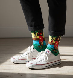Qorapa LaraLara crew socks featuring a vibrant multi-colored narrative graphic print worn with white sneakers
