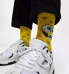 Qorapa LaraLara yellow SpongeBob SquarePants crew socks with porous pattern worn with white sneakers and black pants