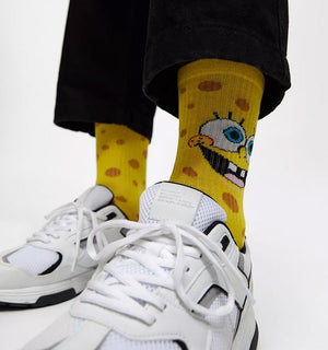 Qorapa LaraLara yellow SpongeBob SquarePants crew socks with porous pattern worn with white sneakers and black pants