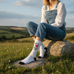 Qorapa LaraLara white crew socks with a cute cow illustration and Sweet Milk text, worn by a woman in a field.