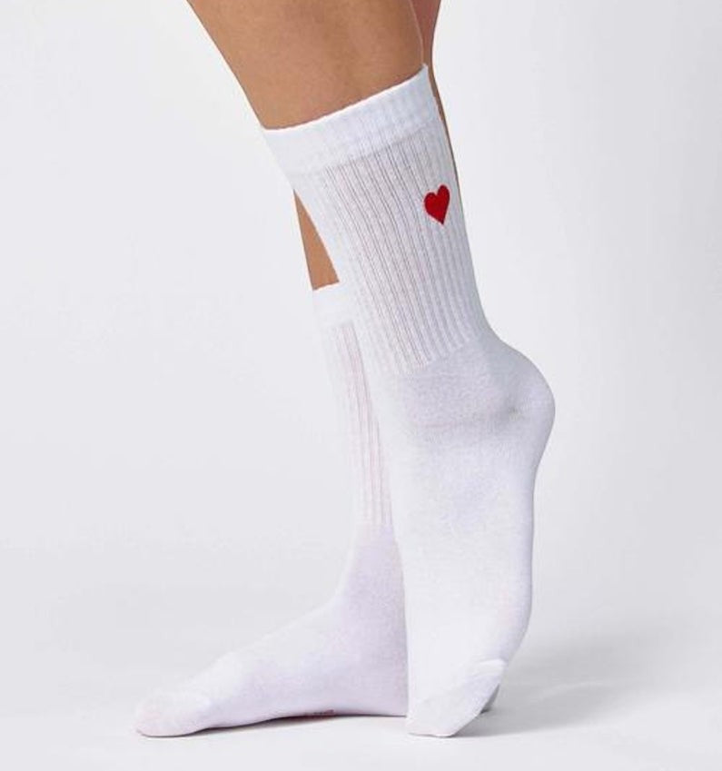 Qorapa LaraLara white cotton crew socks featuring a small embroidered red heart on the ribbed cuff worn on feet