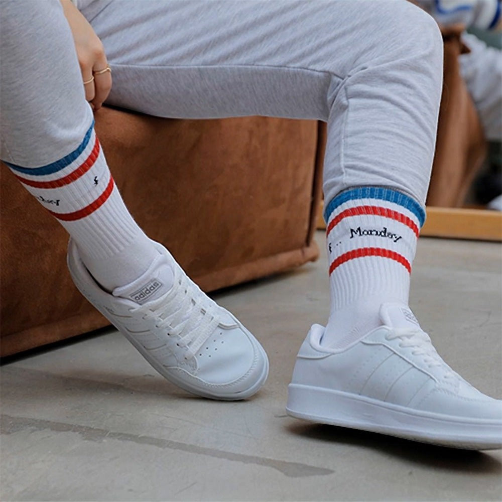 Qorapa LaraLara white low-top athletic sneakers worn with striped crew socks, featuring a minimalist court design.
