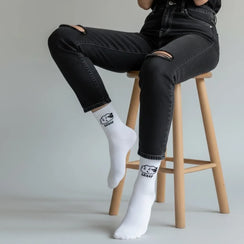 Qorapa LaraLara white crew socks with a minimalist sheep graphic worn by a person in black distressed jeans